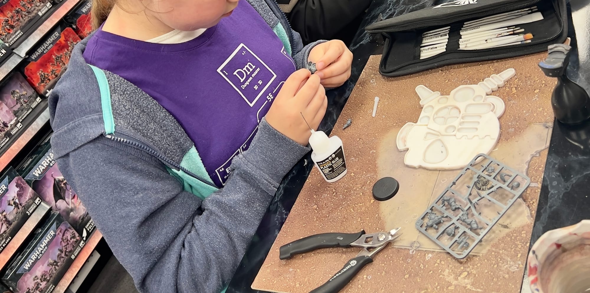 A young girl assembles a free Citadel miniature of the month at a Warhammer shop in Worthing