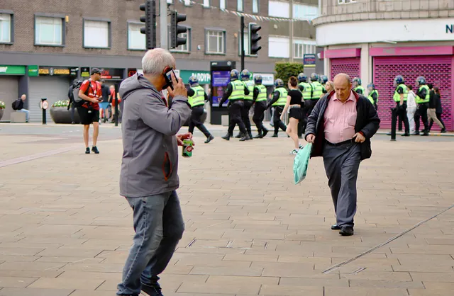 a street scene with a group of police officers in high-visibility vests walking in formation in the background.