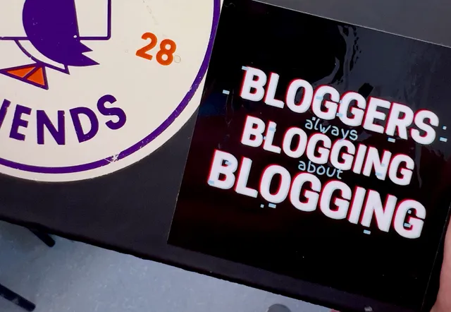 A sticker on the outside of an iPad that reads "bloggers always blogging about blogging". 
